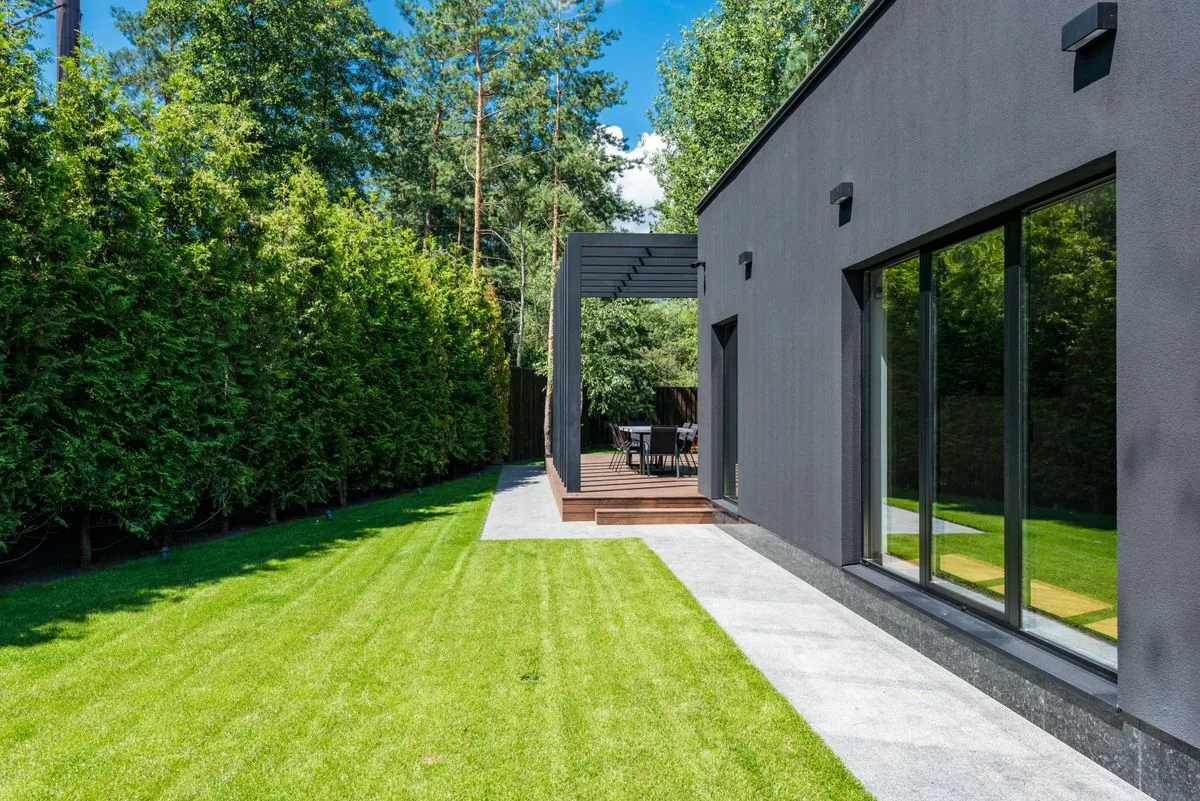 Exterior de casa moderna con patio verde y área de estar al aire libre