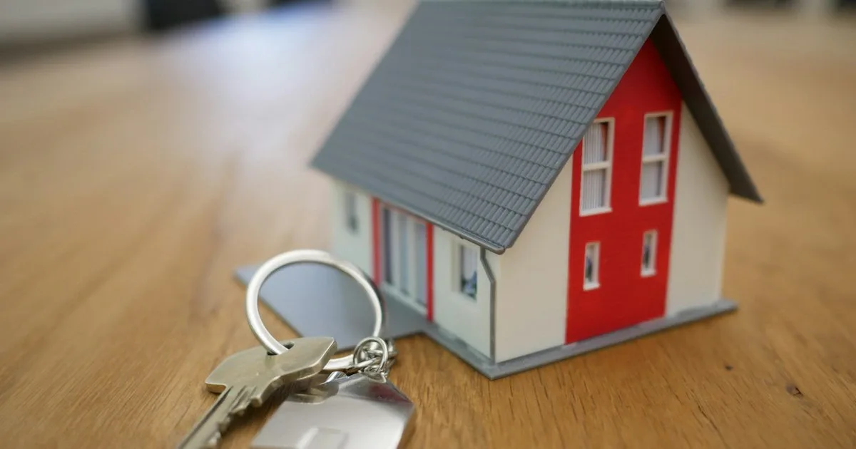 Llaves de casa con llavero en forma de hogar sobre una mesa de madera